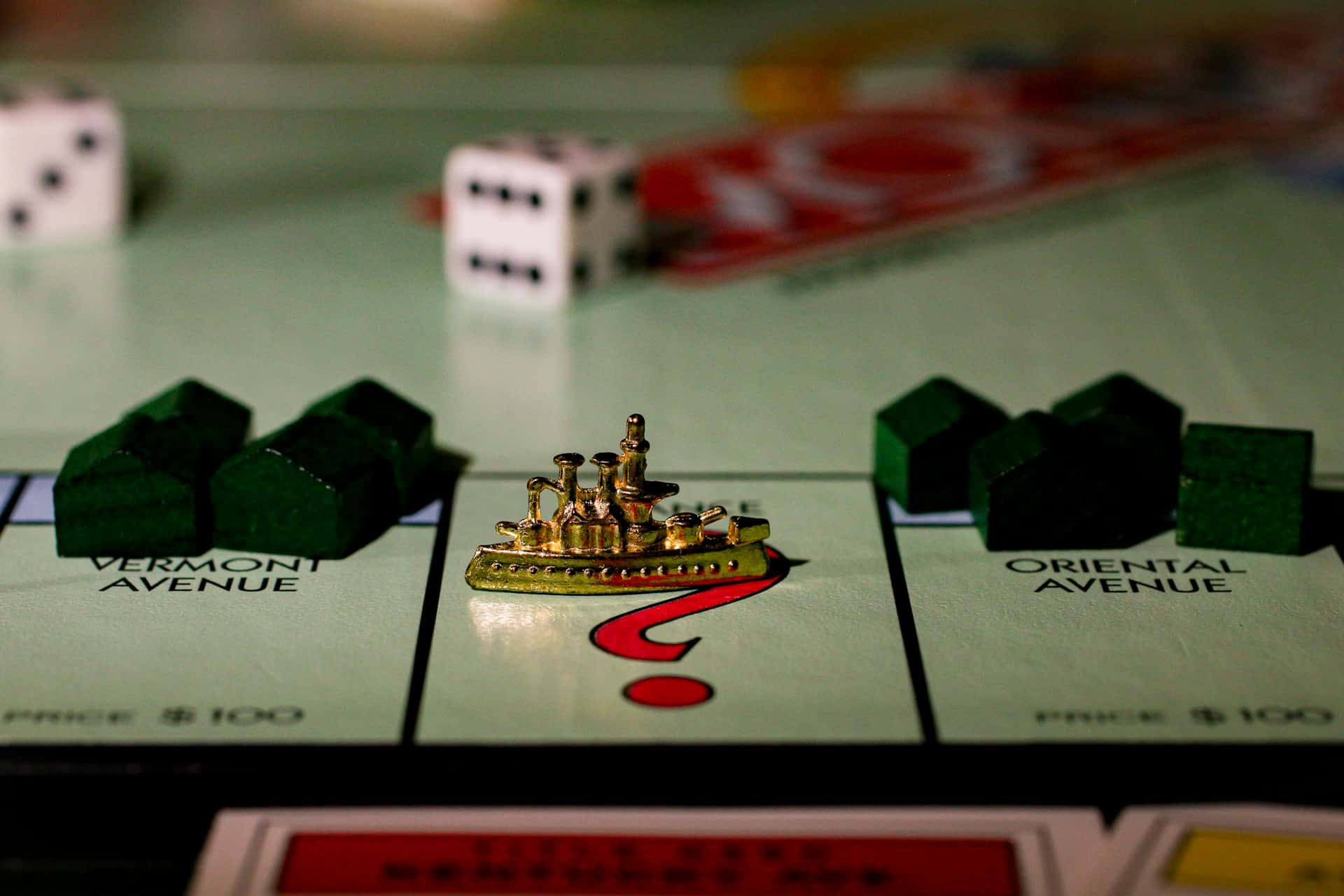 Monopoly token, houses, and dice on a game board.