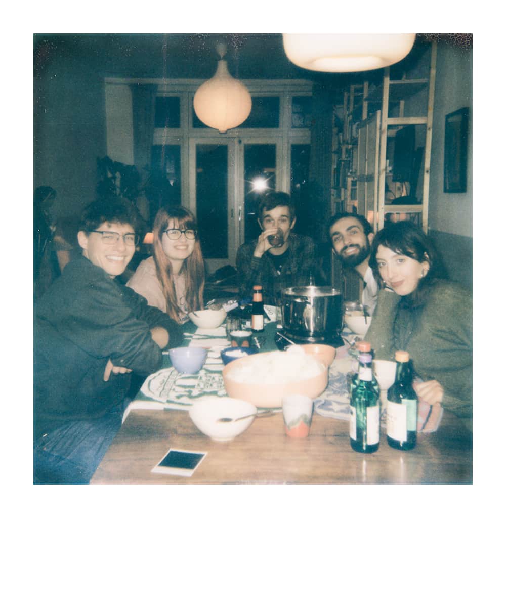 Five friends gathered in a cozy living room around a table with maps and drinks during a tabletop RPG session