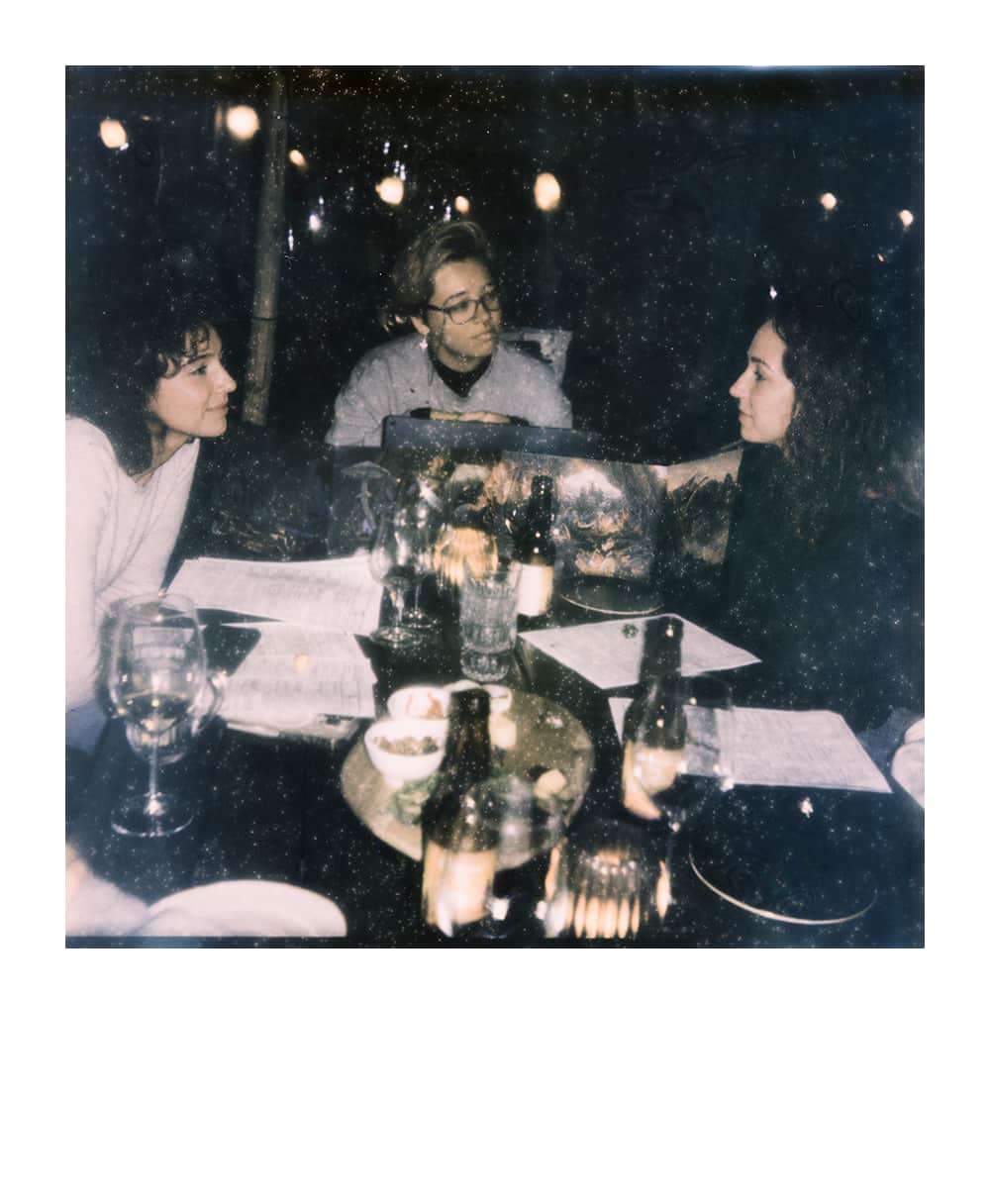 Group playing a tabletop RPG in a café behind a table with snacks, led by a professional Game Master behind a DM screen.