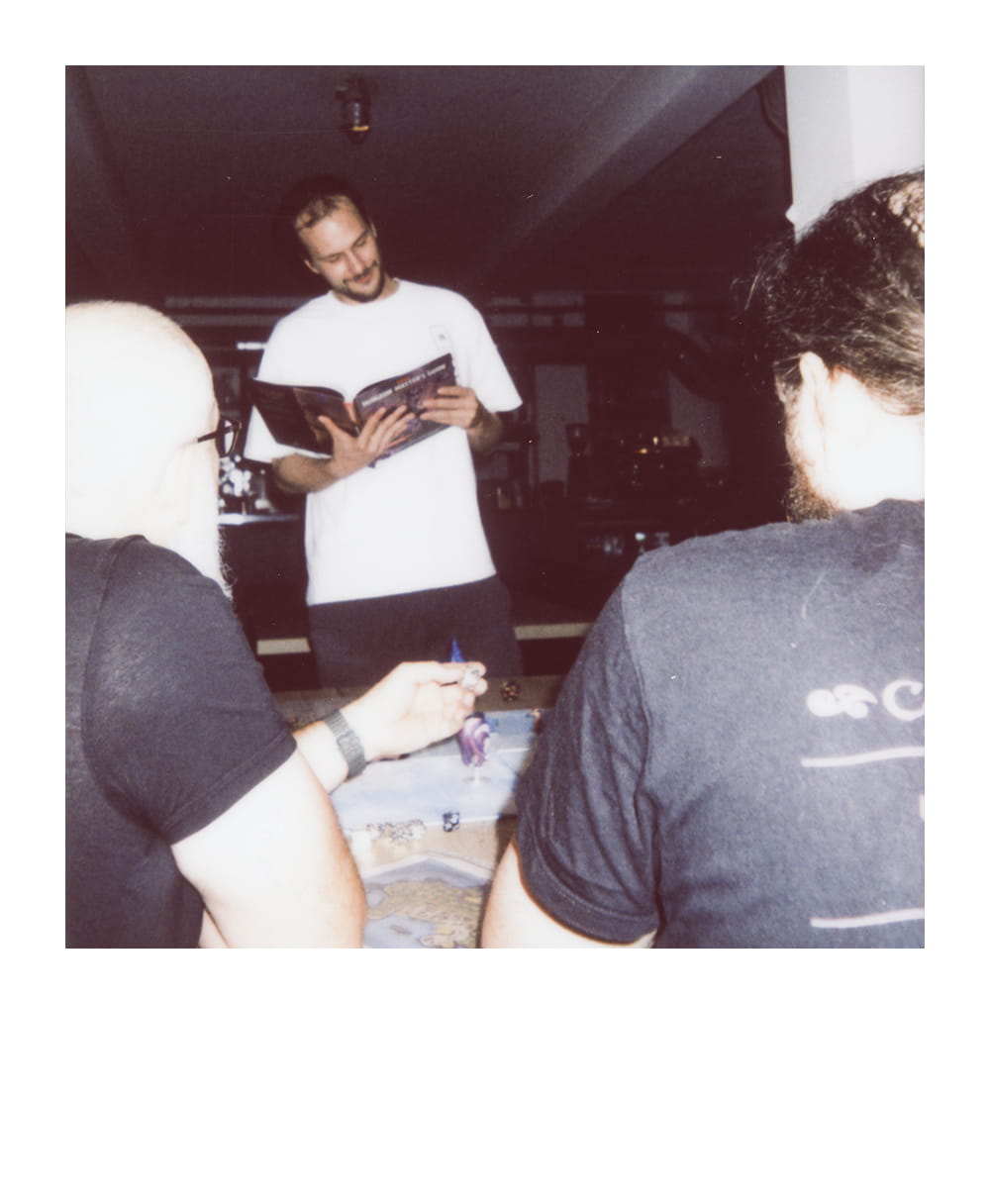 Dungeon Master reads from a rulebook while players follow the tabletop fantasy adventure.